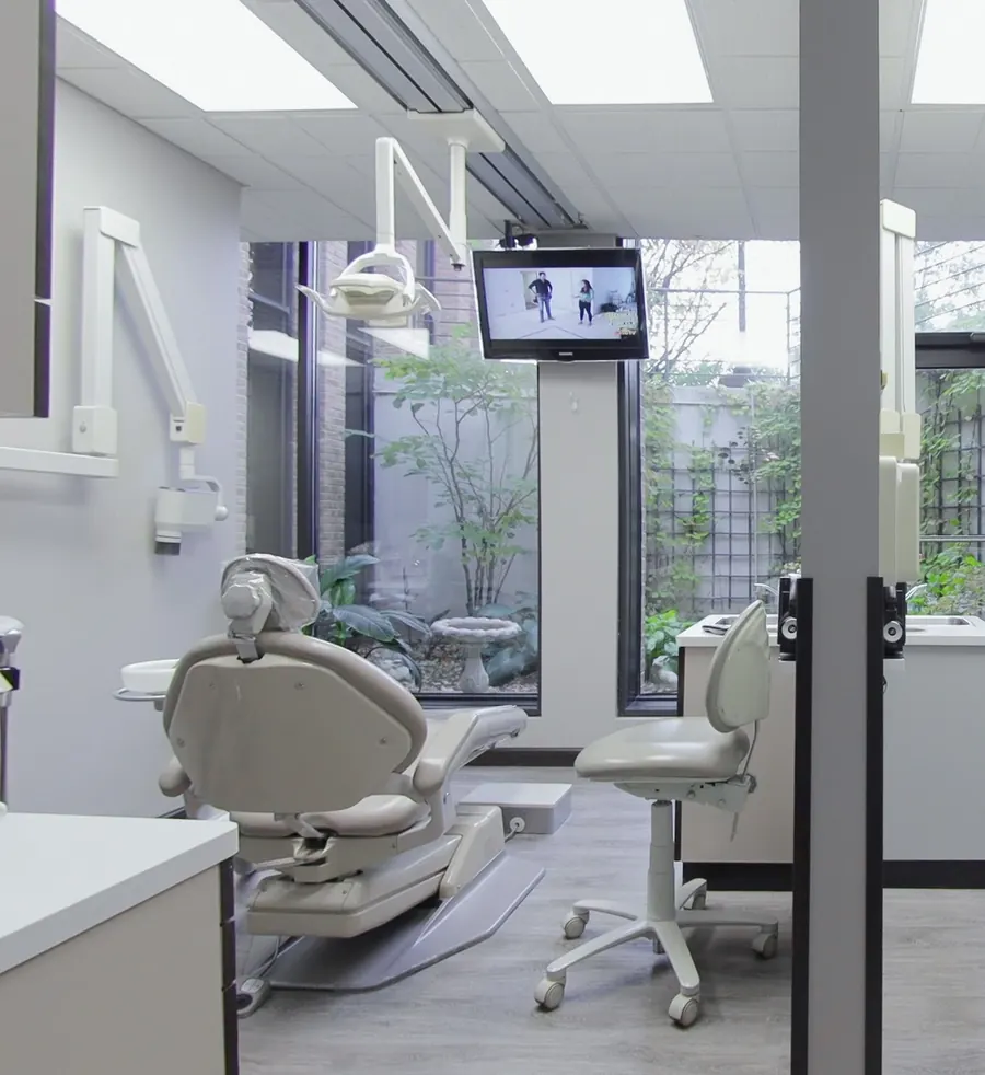 A treatment room with a ceiling-mounted screen and a courtyard window.